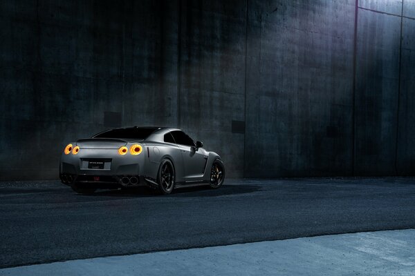 A gray Nissan stands in the semi-darkness