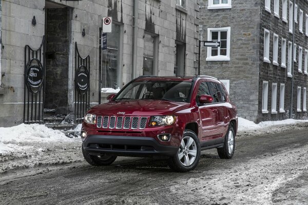 Красный автомобиль фирмы Jeep стоит по-середине улицы