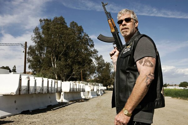 Biker from the TV series with a kalashnikov in his hand on the background of the street