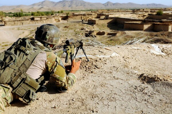 A military man aims a rifle at the ruins