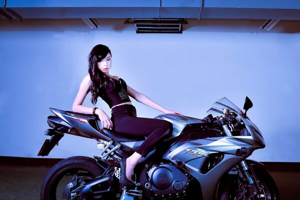 A chic motorcycle and a beautiful slender brunette riding on it