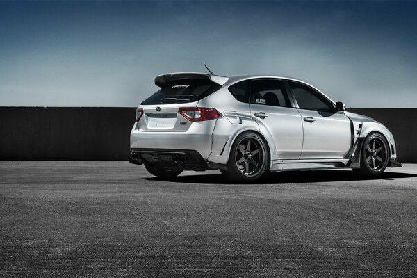 A gray Subaru Impreza WRX car is parked on an asphalt lot