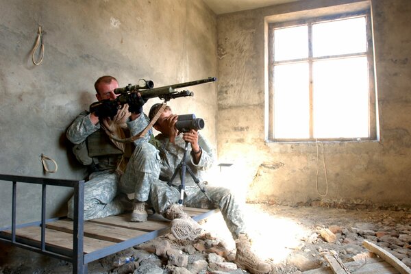 Soldiers with rifles in a destroyed building are ready to fire