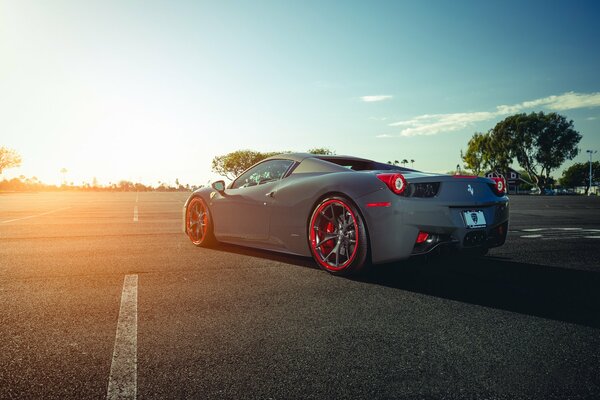 Ferrari with red wheels on the background of the sun