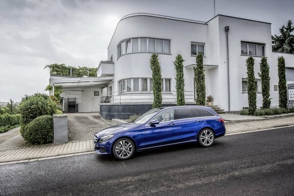 Cobalt Mercedes-Benz on the background of a white two-story house