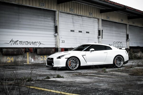 A white Nissan is parked on the road near the paddocks