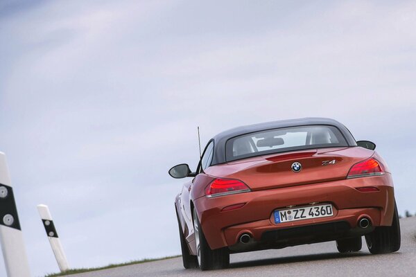 A bronze-colored Bmw z4 is driving on the road