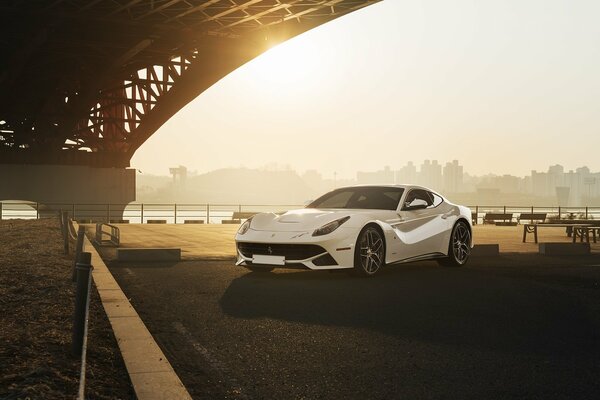 Ferrari blanc sous le pont au coucher du soleil