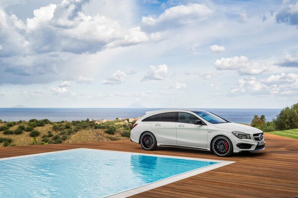 Mercedes stands against the background of the sea by the pool