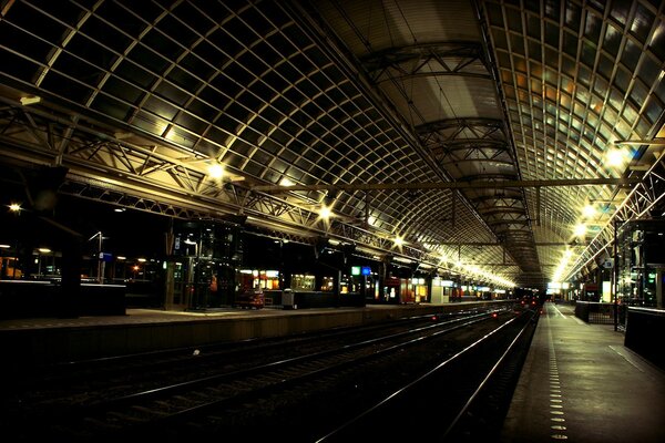 Estación nocturna de ferrocarriles en las luces