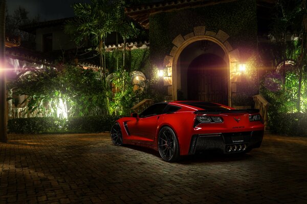 A red chevrolet corvette car stands in the shade