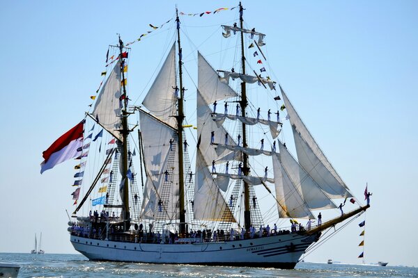 Un barco de vela con la gente en él en el mar contra un cielo azul claro