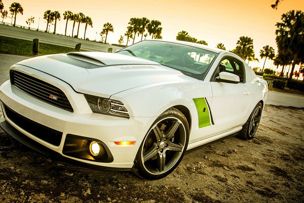 A beautiful white car is parked on the side of the road