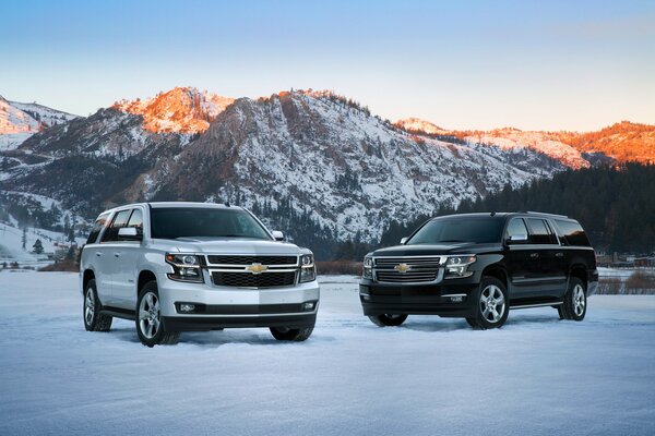 Due SUV Chevrolet stanno sulla neve, dove sullo sfondo sono visibili bellissime montagne innevate