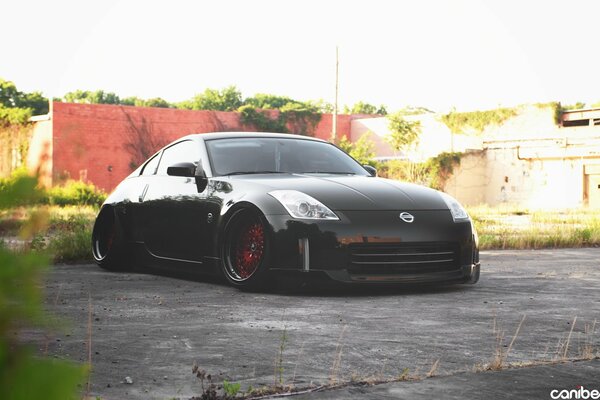 Black tuned nissan on the background of one-story buildings