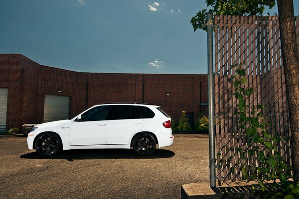 BMW X-5 Biały crossover obok budynku