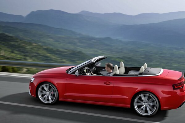 Guy Monte sur un cabriolet dans un paysage de montagne