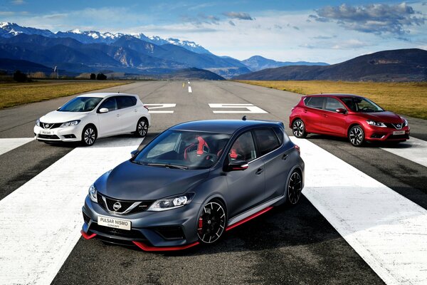 Los autos Nissan de diferentes colores están en la carretera en el fondo de las montañas nevadas