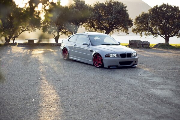 Weißer BMW e46 mit roten Scheiben auf Baumhintergrund