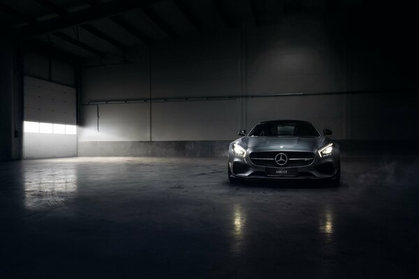 Srebrny mercedes-benz AMG gt w hangarze we mgle