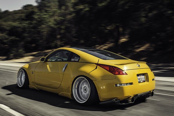 A yellow Nissan is driving on the road