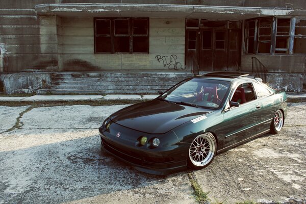 A green Honda stands in an abandoned area