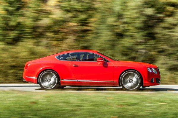 Roter Bentley auf verschwommenem Hintergrund in Bewegung