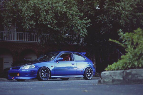 Blue Honda under the balcony of the house