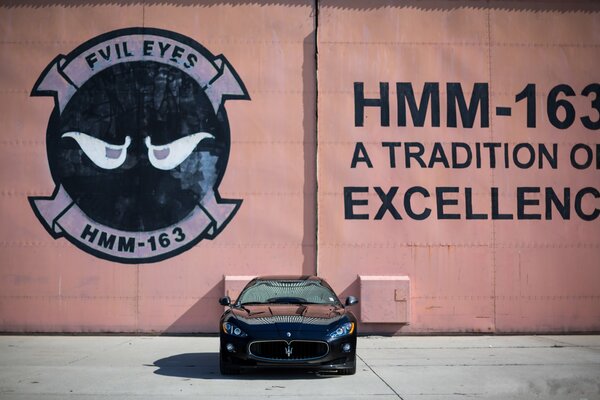Schwarzer Maserati vor Wandhintergrund mit Werbung