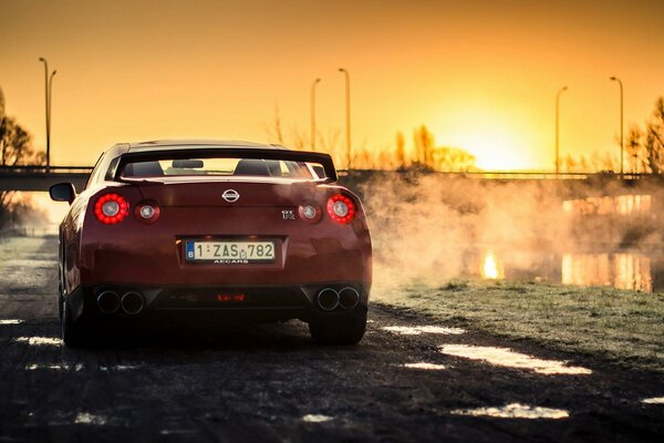 Red sports nissan r35 gt-r on sunset background