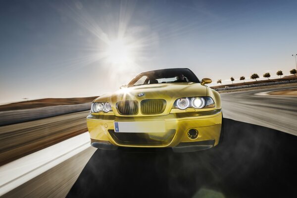 A golden BMW on the road. Sunny day