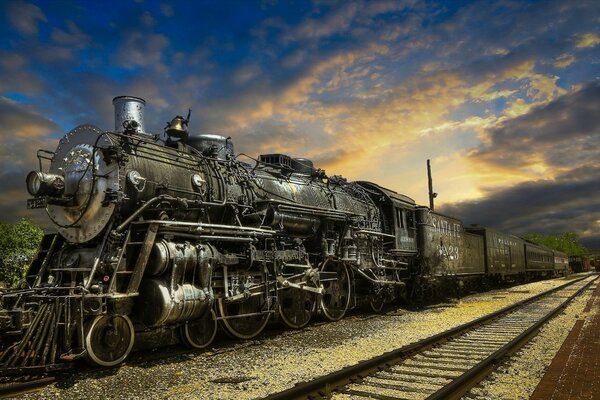 Imagen de la locomotora en el fondo del ferrocarril y la puesta del sol