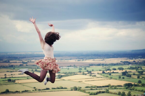 A girl in a jump on the background of a field and clouds