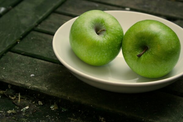 Deux pommes juteuses vertes sur une assiette