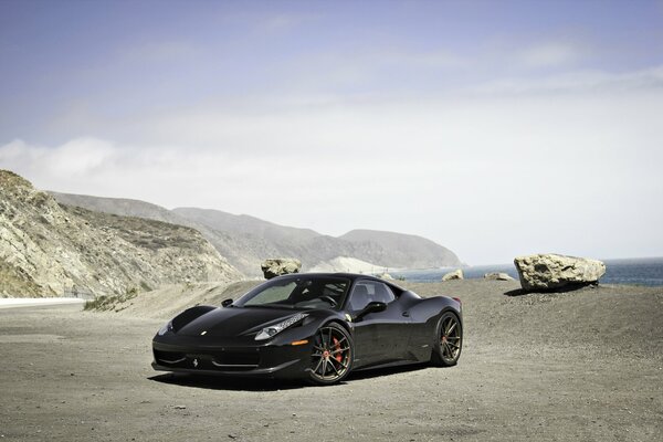 Ferrari nera su uno sfondo di montagne e cielo blu