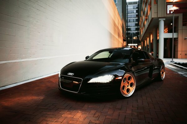 A black audi r8 car stands under the light of a lantern