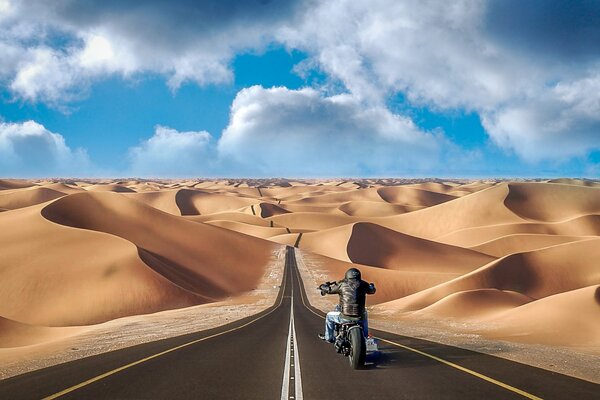 A motorcyclist dissecting the expanses of the desert on the highway among hills and dunes