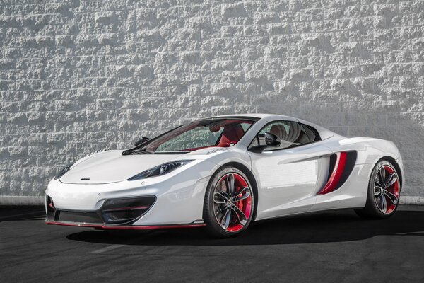 White McLaren sports car on the background of a white stone wall