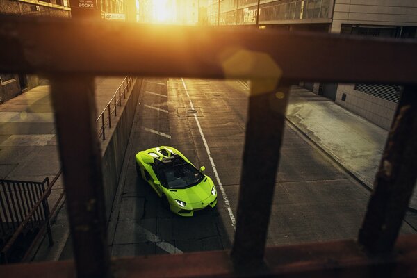 Green supercar in the city at sunset