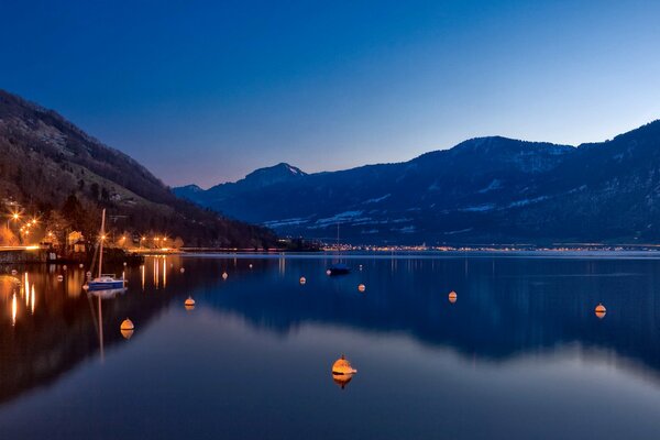 Ciel nocturne, montagnes, rivage avec des lumières