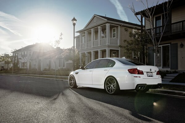 Sotto il cielo soleggiato sulla strada c è una BMW m5f10 bianca