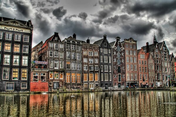 Picturesque Amsterdam houses on the canal bank under a gloomy leaden sky