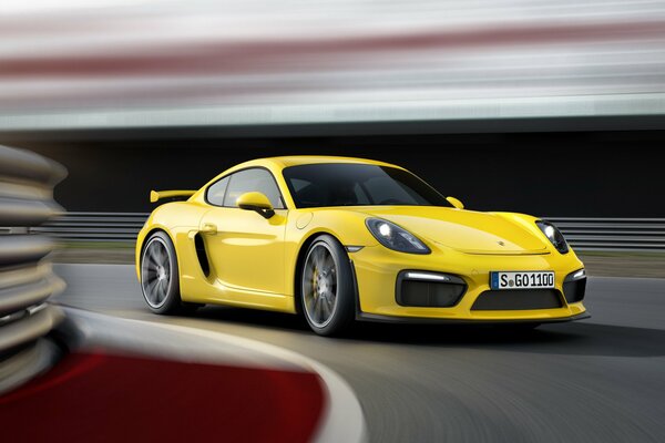 Porsche Cayman amarillo a alta velocidad entra en una curva