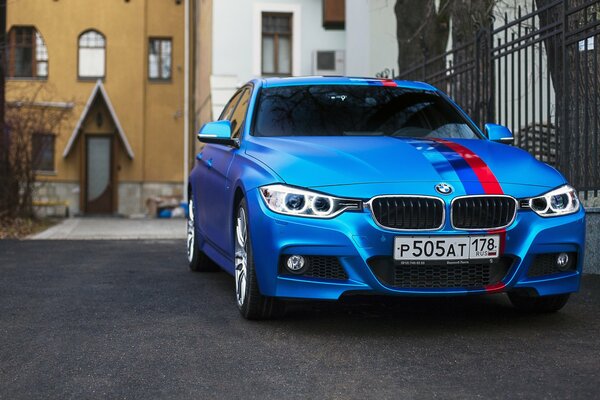 Blauer BMW mit Flagge auf dem Hintergrund der Häuser