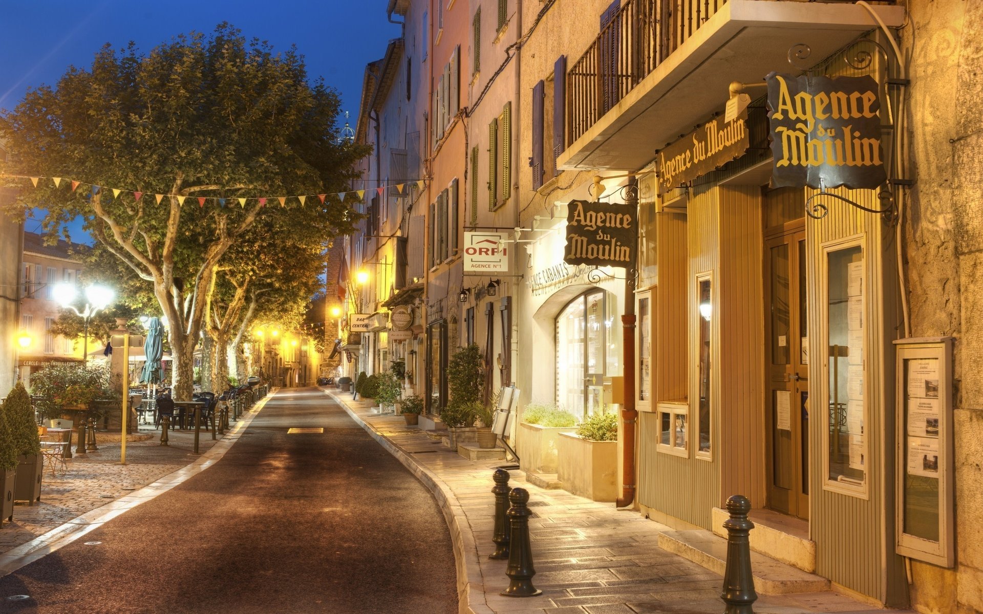 strada alberi sera lanterne viveschi marciapiede luci bandiere vetrine negozi città notte luci della città