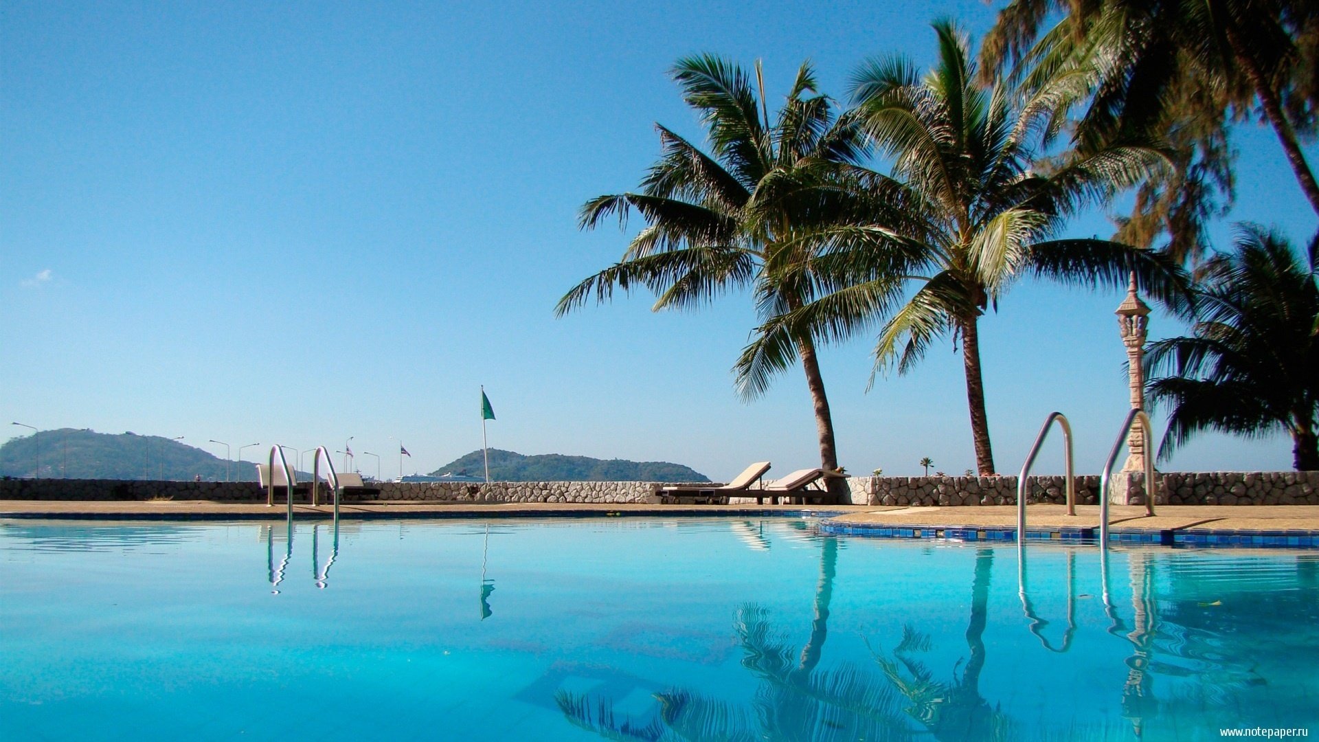 sol piscina palmeras cielo tumbonas verano calor agua clara piedras vista lujo montañas árboles