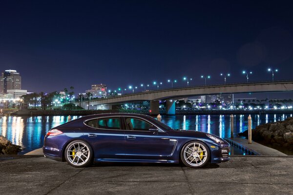 Blue porsche panamera s side view of the night city