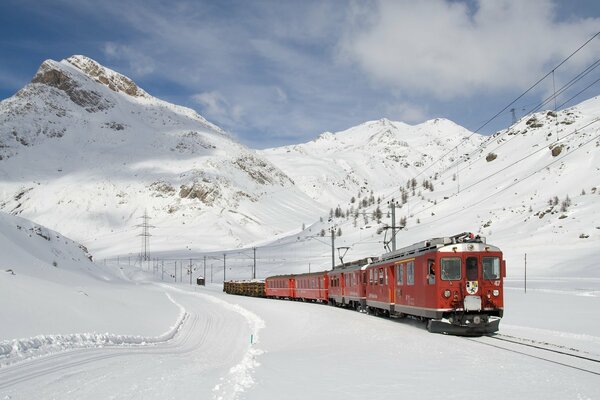 Roter Zug auf dem Hintergrund der schneebedeckten Kehlen