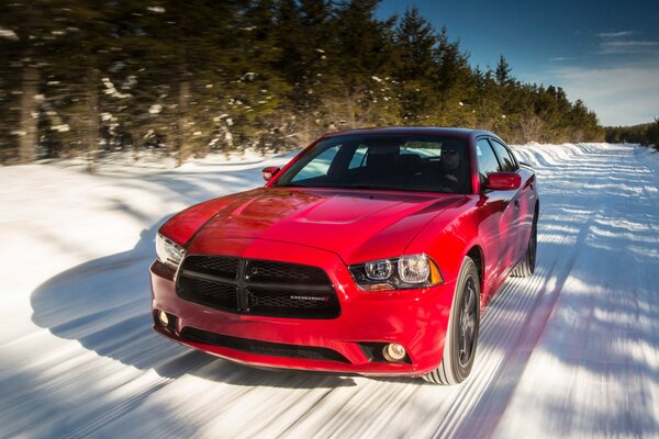 A red car is driving on a snowy road