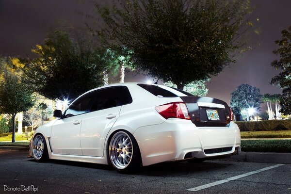 Subaru Impreza blanche dans les lumières de la ville de nuit